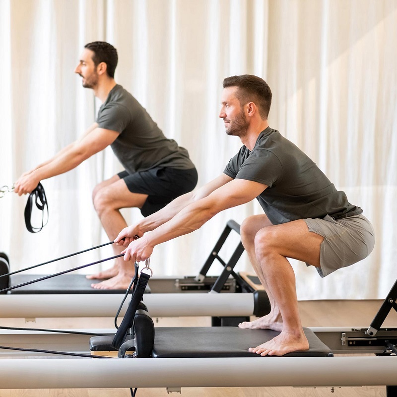 two men are doing exercises in Pilates machine